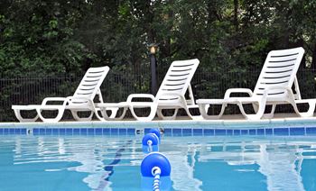 a pool with white chairs and a blue ball in the water  at Fox Pointe Apartments, East Moline, IL